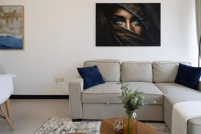 a living room with a couch and a painting of a woman at Large 1BR in JVC Sleeps 4 Rooftop, Pool & Gym in Dubai