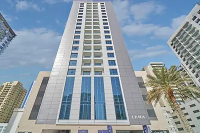a tall building with a palm tree in front of it at Stella Stays Lana Tower in Dubai