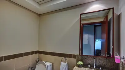 a bathroom with a toilet and a large mirror at 29Boulevard - Modern 2BHK by Radiance Vacation Stays in Dubai