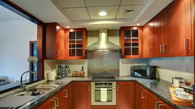 a kitchen with wooden cabinets and a stove top oven at 29Boulevard - Modern 2BHK by Radiance Vacation Stays in Dubai