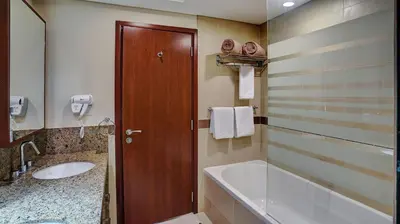 a bathroom with a tub and a sink and a toilet at 29Boulevard - Modern 2BHK by Radiance Vacation Stays in Dubai