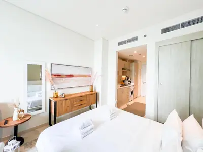 a white bedroom with two beds and a television at Luxurious Sea-View Studio in Seven Palm - 20AB8 in Dubai