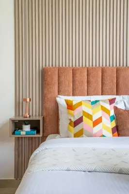 a bed with a orange headboard and colorful pillows at Frank Porter - Riviera 27 in Dubai