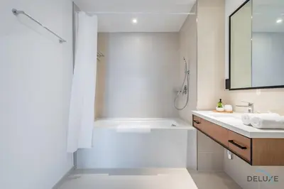 a white bathroom with a shower and a sink at Delightful 2BR Apartment in VIDA Residences Dubai Marina by Deluxe Holiday Homes in Dubai