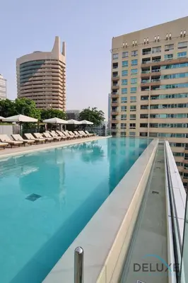 a large swimming pool with chairs and buildings at Delightful 2BR Apartment in VIDA Residences Dubai Marina by Deluxe Holiday Homes in Dubai