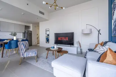 a living room with a white couch and a kitchen at Guest Favourite! Beautiful 1 bedroom apartment in Dubai