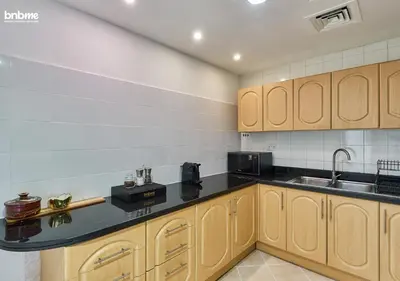a kitchen with wooden cabinets and a black counter top at bnbmehomes - DAMAC Waves Tower in Dubai