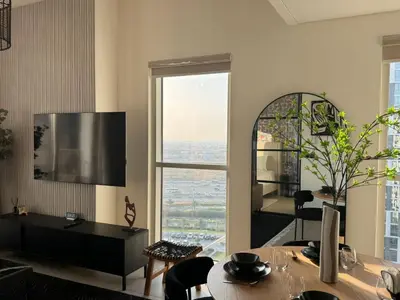 a living room with a table and a large window at Oraya - Brand New 2BR Apt in Socio Tower at Dubai Hills in Dubai