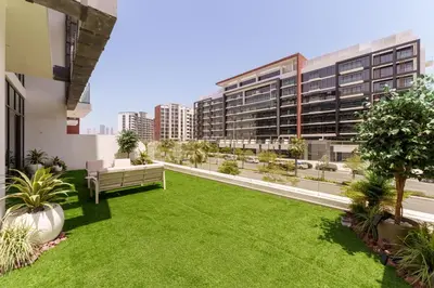an apartment patio with grass and benches and buildings at Chic 1BR Apartment in Azizi Riviera, Meydan in Dubai