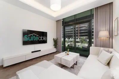 a living room with a white couch and a tv at Chic 1BR Apartment in Azizi Riviera, Meydan in Dubai