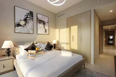 a bedroom with a large white bed with a table on it at Livbnb - 3BR Deluxe suite w/ Burj Khalifa & Fountain Views in Dubai