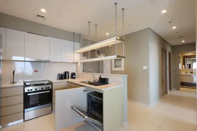 a kitchen with white cabinets and a sink and a stove at Livbnb - 3BR Deluxe suite w/ Burj Khalifa & Fountain Views in Dubai