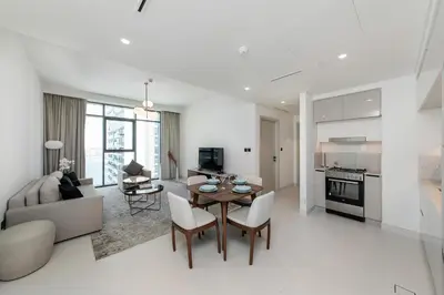 a white living room with a table and chairs at Chic Apartments in Marina Vista Emaar Beachfront in Dubai