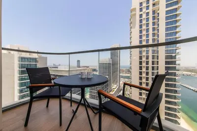 a table and chairs on a balcony with a view of the city at Chic Apartments in Marina Vista Emaar Beachfront in Dubai