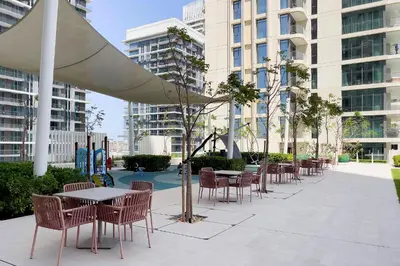 a patio with tables and chairs and a playground at Chic Apartments in Marina Vista Emaar Beachfront in Dubai