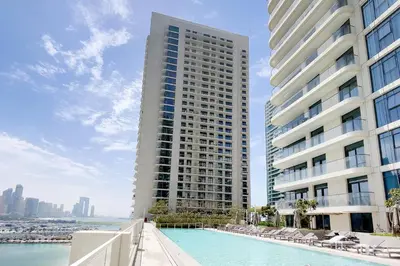 a large building with a swimming pool in front of a building at Chic Apartments in Marina Vista Emaar Beachfront in Dubai