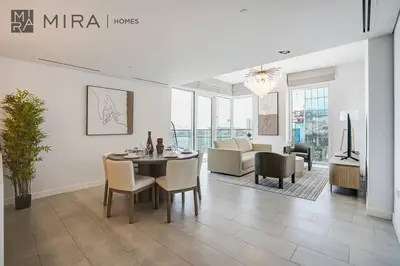 a dining room with a table and a living room at Mira Holiday Homes - Luxury 2 bed apartment in La Vie in Dubai