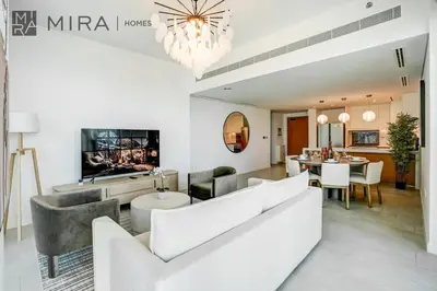 a living room with a couch and a dining room at Mira Holiday Homes - Luxury 2 bed apartment in La Vie in Dubai