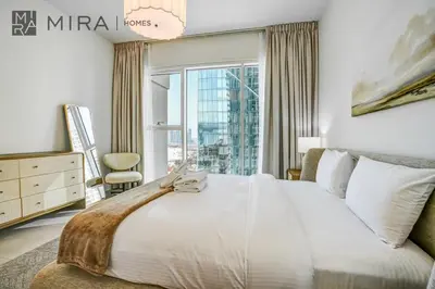 a bedroom with a large bed with a large window at Mira Holiday Homes - Luxury 2 bed apartment in La Vie in Dubai