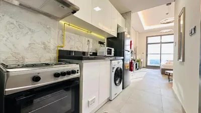 a kitchen with a stove and a washer and dryer at Oval Tower Furnished Studio Business Bay in Dubai