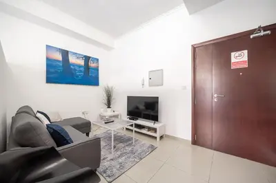 a living room with a couch and a tv and a door at StoneTree - Chic Studio - Near Beach in Dubai