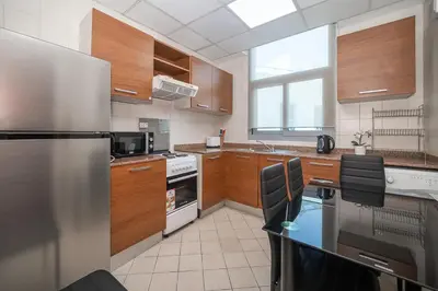 a kitchen with a refrigerator and a table in it at StoneTree - Chic Studio - Near Beach in Dubai