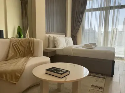 a hotel room with two beds and a table and a couch at ASHRI HH, STANDARD STUDIO IN STUDIO CITY in Dubai