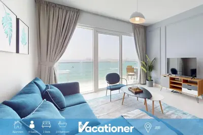 a living room with a blue couch and a large window at La Vie JBR - Breathtaking Two Bedroom in Dubai