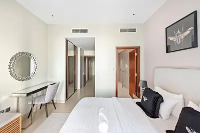 a white bedroom with a bed and a desk at Luxury 2BR with Marina Views Near Dining Shopping Attractions & Beaches in Dubai