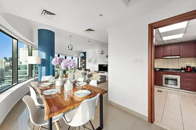 a kitchen and dining room with a wooden table and chairs at Dubai Marina 3BR Apartment, Steps to Marina Walk, Marina Beach & JBR in Dubai