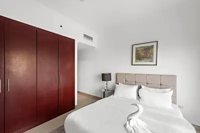 a bedroom with a large bed with wooden cabinets at Dubai Marina 3BR Apartment, Steps to Marina Walk, Marina Beach & JBR in Dubai