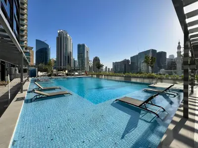 a swimming pool with lounge chairs and a city skyline at Modern Studio Downtown DT1, Walk to Dubai Mall, Burj View & Metro in Dubai