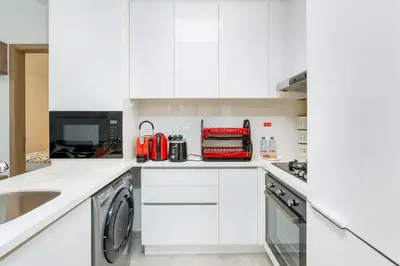 a white kitchen with a sink and a dishwasher at Nice apartment in JVC - Dubai in Dubai