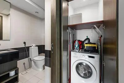 a bathroom with a washing machine and a toilet at FIRST CLASS 1BR Premium & Spacious City Escape in Dubai