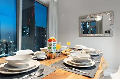 a wooden table with white bowls and plates on it at FIRST CLASS 1BR Premium & Spacious City Escape in Dubai