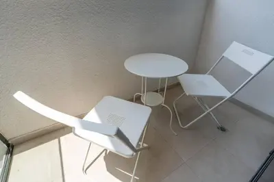 two white chairs and a table in a room at 12 min from downtown - Studio - Azizi Riviera in Dubai