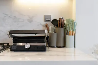 a toaster oven sitting on a counter with utensils at 1 bedroom - 12 min from downtown - Azizi Riviera in Dubai