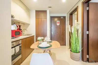 a small kitchen with a table and a red microwave at Calm 1BR in Vera Tower, Business Bay by Deluxe Holiday Homes in Dubai