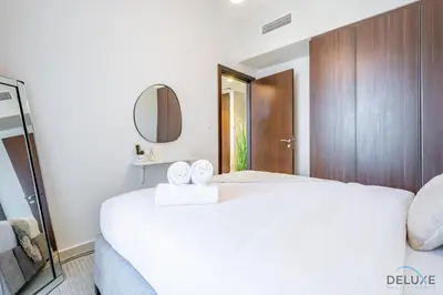 a bedroom with a large white bed and a mirror at Calm 1BR in Vera Tower, Business Bay by Deluxe Holiday Homes in Dubai