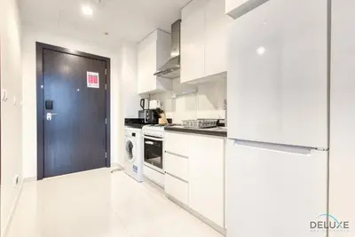 a kitchen with white cabinets and a blue door at Charming Studio in Celestia A, Dubai South by Deluxe Holiday Homes in Dubai