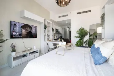 a bedroom with a white bed with a tv on the wall at Nice studio in Arjan - Dubai in Dubai