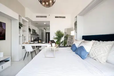 a bedroom with a large white bed and a kitchen at Nice studio in Arjan - Dubai in Dubai