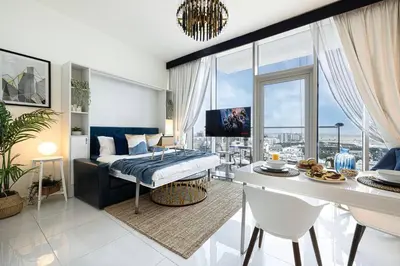a bedroom with a bed and a living room with a table at Studio - Miraclz Tower in Arjan in Dubai