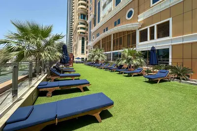 a row of chaise lounges on a lawn in a building at Lux 2BD apartment, Steps to the Beach in the Heart of Dubai Marina - Elite Residence Tower in Dubai