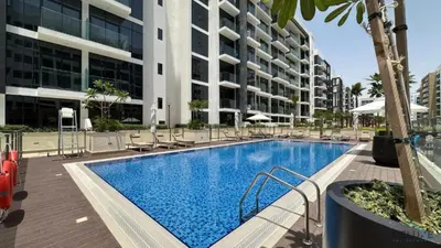 a swimming pool with chairs and a building at Appealing Studio Apartment at Azizi Riviera 34, Al Merkadh by Deluxe Holiday Homes in Dubai
