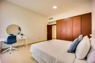 a bedroom with a bed and a desk and a chair at 2BD apartment near the beach in Bahar, JBR in Dubai