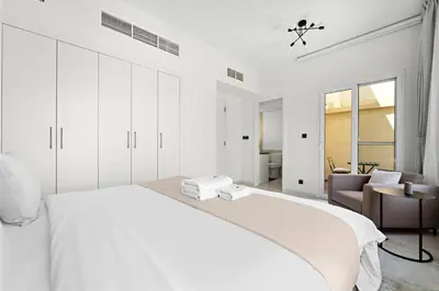 a white bedroom with a bed and a chair at Stonetree - The Springs 5 - Peaceful Community in Dubai
