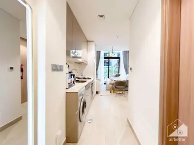 a kitchen and living room with a washer and dryer at Elegance at Aziz Riviera Studio & Balcony in Dubai