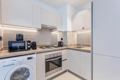 a kitchen with white cabinets and a washer and dryer at STAY BY LATINEM Luxury 1BR Holiday Home CV B803 near Burj Khalifa in Dubai
