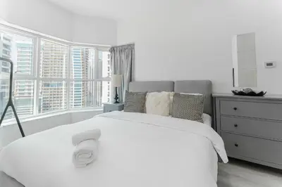 a white bedroom with a large bed and a window at HAVN - Studio with Lake Views in Dubai Gate, JLT in Dubai